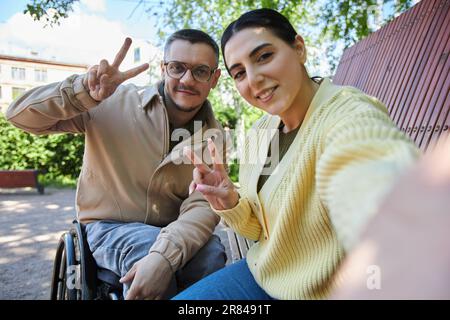 Selfie-Porträt einer jungen Frau, die zusammen mit ihrer Freundin mit Behinderung im Freien vor der Kamera posiert Stockfoto