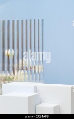 Weißer Sockel zeigt blauen Hintergrund mit modernem Transparentstreifen-Glas und Blume mit Sonnenlicht Stockfoto
