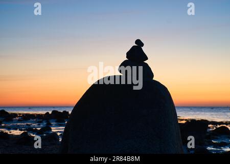 Steinpyramide an der Ostsee mit Blick auf das Meer bei Sonnenuntergang und Blue Hour. Steine als Silhouette. Spirituelle Sichtweise. Landschaftsaufnahmen von Poel Island Stockfoto
