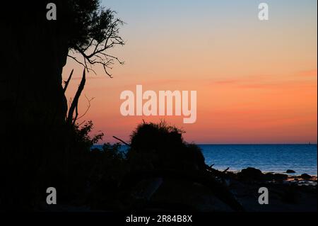 Steile Küste auf der Insel Poel bei Sonnenuntergang mit Blick auf den pastellfarbenen Himmel über Felsen in der Ostsee. Landschaftsaufnahmen von der Küste Stockfoto