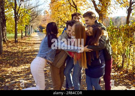 Eine Gruppe glücklicher junger Freunde, die Spaß im Herbstpark haben. Stockfoto