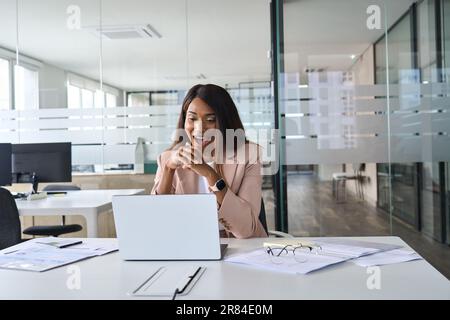 Aufgeregt überraschte afroamerikanische Geschäftsfrau, die sich im Büro ein Notebook ansieht. Stockfoto
