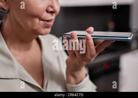 Nahaufnahme einer modernen Seniorin, die Sprachnachrichten per Smartphone zu Hause aufnimmt, Kopierbereich Stockfoto