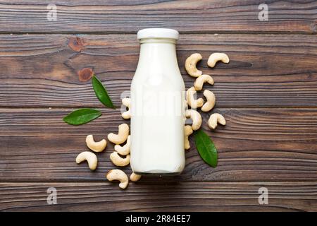 Vegane Milch aus Cashews in Flaschen auf einem Holztisch, vegetarische Alternative Lebensmittel, sauberes Esskonzept. Draufsicht mit Kopierbereich. Stockfoto