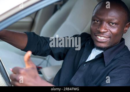 Lächelnder afrikanischer Fahrer, der Daumen nach oben zeigt, dass er einverstanden ist Stockfoto