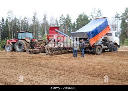 Sämaschine, Mähdrescher, Sämaschine und Lkw, Kipper und Arbeiter auf dem Feld. Stockfoto