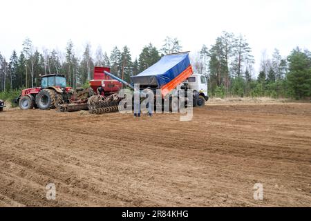 Sämaschine, Mähdrescher, Sämaschine, Traktor und LKW, Kipplaster und Arbeiter auf dem Feld. Stockfoto