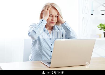 Reife Geschäftsfrau mit starken chronischen Kopfschmerzen, Migräne oder Gedächtnisstörungen bei der Arbeit, Stressgefühl und Ermüdung, Frau mittleren Alters Stockfoto