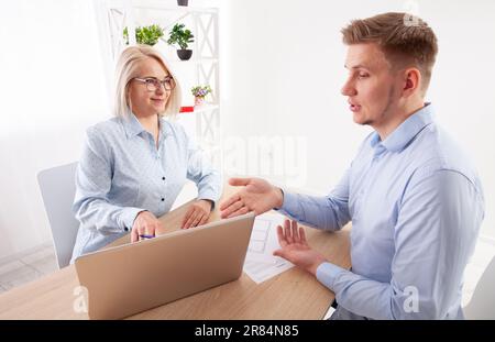 Ältere Geschäftsfrau, die als Mentorin für Brillengläser tätig ist und mit verschiedenen Führungskräften am Konferenztisch des Vorstands einen Wachstumsplan aushandelt Stockfoto