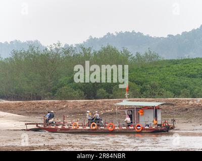 Einfache Autofähre nach Überquerung eines Flusses in der Provinz Thanh Hoa in Vietnam mit Passagieren und ein paar Motorrädern, die von Bord gehen. Stockfoto