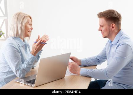 Ältere Mentorin von ceo und Geschäftsfrau verhandelt Wachstumsplan mit einer vielseitigen Führungskraft am Konferenztisch mit Laptop Stockfoto