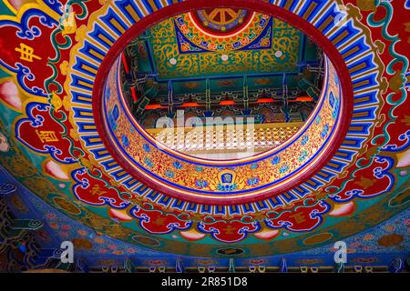 Flacher Blick auf eine komplexe, lebendige chinesische Zaojing-Decke mit symmetrischen goldenen Mustern, roten runden Rahmen und detaillierten Kunstwerken Stockfoto