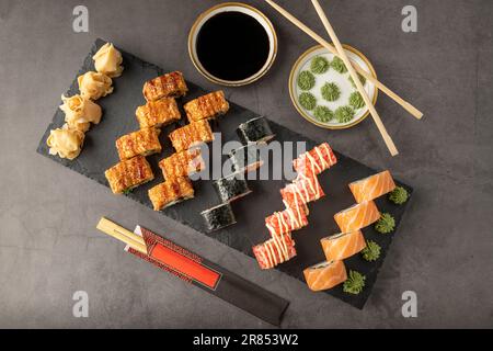 Sushi-Set mit verschiedenen Produkten auf einem schwarzen Steinteller. Verwischen Sie den Hintergrund und den selektiven Fokus Stockfoto