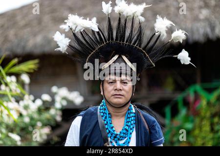 Ein Mann aus dem Adi-Stamm aus dem Nordosten Indiens, gekleidet in traditioneller Kleidung mit Spezialhut und Federn auf dem Kopf, Assam, Indien Stockfoto