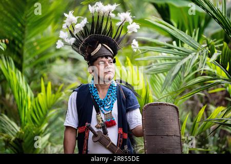 Ein Mann aus dem Stamm der Adi aus dem Nordosten Indiens, gekleidet in traditioneller Kleidung, mit einem speziellen Hut mit Federn, Dolch und einem Schild, Assam Stockfoto