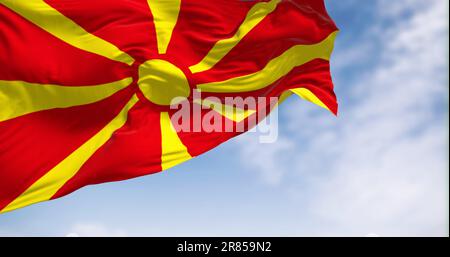 Die Nationalflagge Nordmazedoniens, die an klaren Tagen im Wind winkt. Stilisierte gelbe Sonne mit acht Strahlen, die sich bis zu den Rändern eines roten Feldes erstrecken Stockfoto