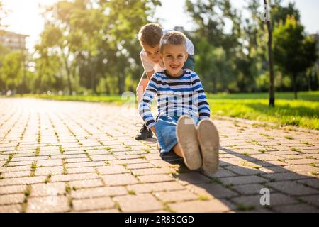 Zwei Jungs haben Spaß beim Skateboard im Park. Verspielte Kinder im Park, glückliche Kindheit. Stockfoto