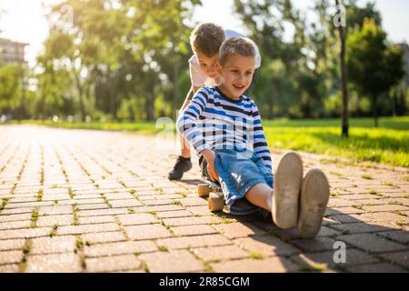 Zwei Jungs haben Spaß beim Skateboard im Park. Verspielte Kinder im Park, glückliche Kindheit. Stockfoto