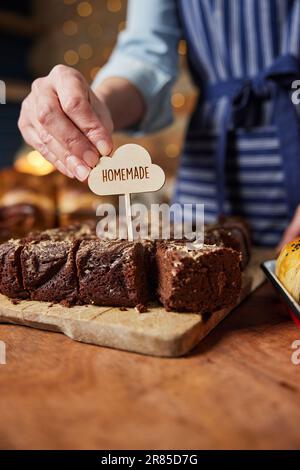 Verkaufsassistent In Der Bäckerei, Der Hausgemachte Etiketten In Frisch Gebackene Schokoladen-Brownies Macht Stockfoto