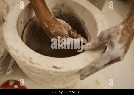 Afrikanischer Keramiker, der an einem Tontopf in einer Studiowerkbank arbeitet Stockfoto