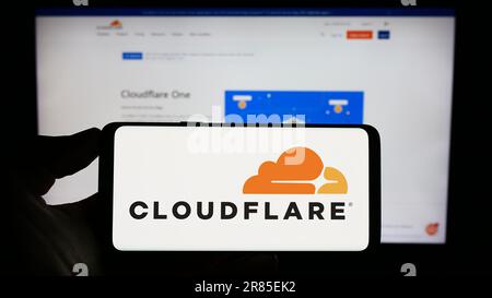 Person, die ein Mobiltelefon mit dem Logo des US-amerikanischen ICT-Unternehmens Cloudflare Inc. Auf dem Bildschirm vor der Unternehmenswebseite hält. Konzentrieren Sie sich auf das Display des Telefons. Stockfoto