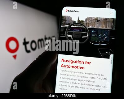 Person mit Smartphone und Webseite des niederländischen Unternehmens TomTom NV auf dem Bildschirm mit Logo. Konzentrieren Sie sich auf die Mitte des Telefondisplays. Stockfoto