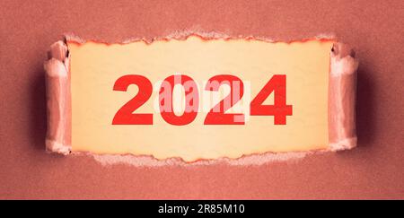 Öffne das neue Jahr. 2024 Schriftzug auf zerrissenem Papppapier Stockfoto