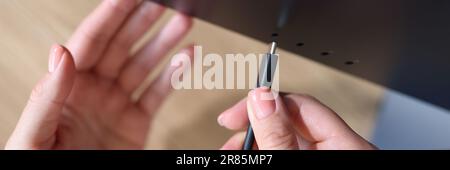 Person Hand verbindet ein schwarzes USB-C- oder Typ C-Netzkabel mit dem Computer Stockfoto