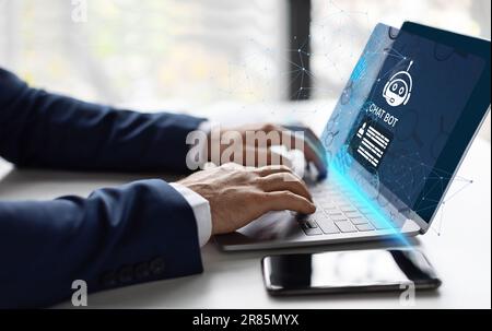 Ein unerkannter Geschäftsmann, der auf der Tastatur eines Laptops tippt und Chatbot benutzt Stockfoto
