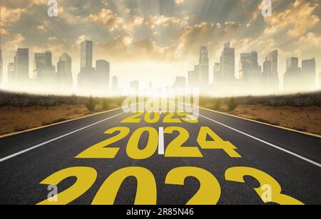 Das Wort 2024 bis 2028, das auf der Autobahn geschrieben wurde, mitten auf einer leeren Asphaltstraße bei Sonnenaufgang. Neujahrskonzept 2024. Planungskonzept Stockfoto