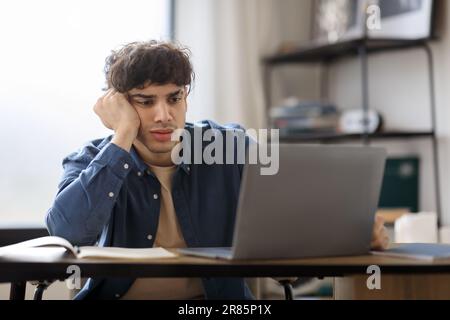 Gelangweilter Arabischer Geschäftsmann, Der Auf Dem Laptop Sitzt Und Im Modernen Büro Arbeitet Stockfoto
