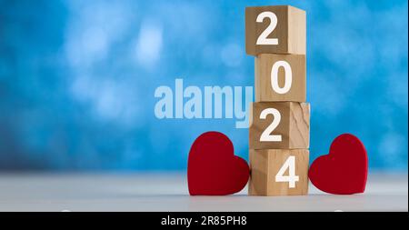 Ich liebe das Jahr 2024. Neujahr und Liebeskonzept. Jahr 2024 Inschrift auf zwei Herzen und Holzwürfel. Stockfoto