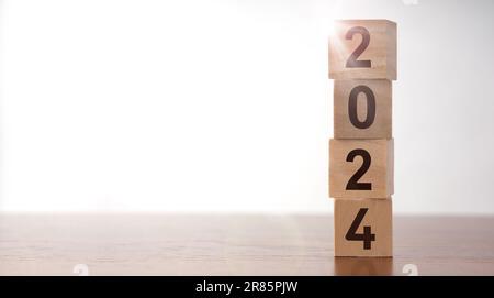 2024 Happy New Year Background für Grafik. 2024 Zahl auf hölzernen Würfelblöcken auf weißem Hintergrund mit Kopierbereich. Willkommen im Neujahrskalender Stockfoto