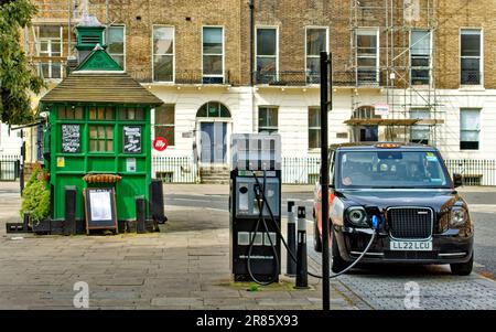 London Camden Russell Square, ein grüner Cabmans Shelter und ein Taxi an der ESB-Ladestation Stockfoto