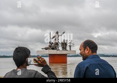 Guwahati, Indien. 17. Juni 2023. Ein Mann spricht am Telefon, wie dunkle Wolken über der Statue von Lachit Borphukan schweben, dem Kommandanten des Ahom-Königreichs am Brahmaputra River in Guwahati. Der Wasserstand des Brahmaputra River ist aufgrund starker Regenfälle in Guwahati gestiegen. Die starken Regenfälle verursachten auch Überschwemmungen in mehreren tief liegenden Teilen der Stadt. Kredit: SOPA Images Limited/Alamy Live News Stockfoto