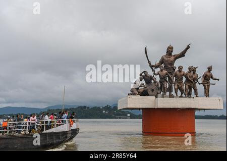 Guwahati, Indien. 17. Juni 2023. Die Menschen fahren in einer Fähre, während dunkle Wolken über der Statue von Lachit Borphukan schweben, dem Kommandanten des Ahom-Königreichs am Brahmaputra River in Guwahati. Der Wasserstand des Brahmaputra River ist aufgrund starker Regenfälle in Guwahati gestiegen. Die starken Regenfälle verursachten auch Überschwemmungen in mehreren tief liegenden Teilen der Stadt. Kredit: SOPA Images Limited/Alamy Live News Stockfoto