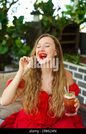 Eine wunderschöne, blonde Russin, die Erdbeeren isst, mit geschlossenen Augen und Vergnügen Stockfoto