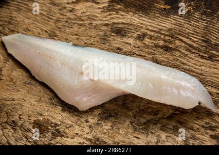 Ein Filet von einem wilden Kabeljau, Gadus morhua, der im Ärmelkanal auf einem Holzbrett gefangen wurde, bevor er selbst gekocht wurde. England GB Stockfoto