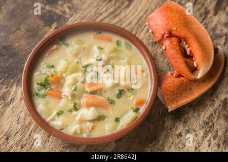 Ein Hummer, Homarus gammarus, der im Englischen gefangen und in einer Suppe gebacken wurde. Serviert in einer Schüssel auf einem Holzbrett mit Hummer Stockfoto