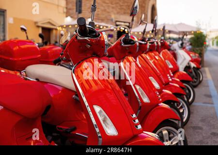 Gruppe roter Vespa-Roller geparkt. Motorroller-Verleih in der Stadt. Stockfoto