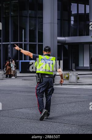 Ein Polizist leitet den Verkehr während der Hauptverkehrszeit in der Innenstadt von Toronto. Ein Polizist, der den Verkehr auf der Straße reguliert. Straßenfoto, Kopierbereich, Sel Stockfoto