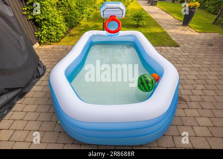 Draufsicht auf den aufblasbaren Kinderpool mit Wasser auf dem Vorhof im Garten der Villa. Stockfoto