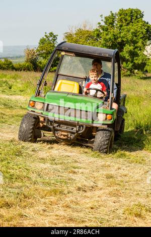 Sechs Jahre alter Junge, der einen John Deere Gator, High Bickington, North Devon, England, Großbritannien, taucht. Stockfoto