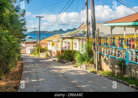 Farbenfrohe Straße mit Wohnhäusern an der Bucht, der Mayreau Insel mit Union Island im Hintergrund, Saint Vincent und die Grenadinen, West Indi Stockfoto