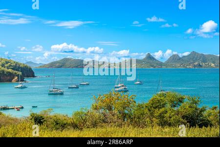 Lagune mit türkisfarbenem Wasser, Yachten und Boote am Mayreau Island Pier mit Union Island im Hintergrund, St. Vincent und die Grenadinen, West Indi Stockfoto