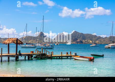 Lagune mit türkisfarbenem Wasser, Yachten und Boote am Mayreau Island Pier mit Union Island im Hintergrund, St. Vincent und die Grenadinen, West Indi Stockfoto