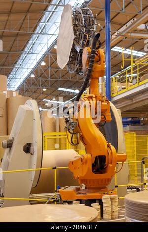 Ein Roboterarm, der große Papierrollen in einer Papierfabrik verpackt. Stockfoto