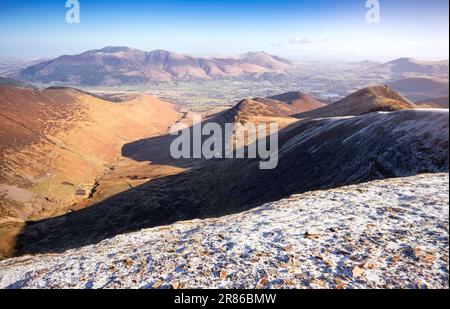 Im englischen Lake District, Großbritannien, blicken Sie vom Gipfel des Crag Hill auf Coledale Beck mit Skiddaw und Blencathra in der Ferne im Winter. Stockfoto