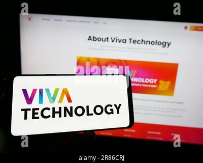 Person, die ein Mobiltelefon mit dem Logo der französischen Konferenz Viva Technology (VivaTech) auf dem Bildschirm vor der Webseite hält. Konzentrieren Sie sich auf das Display des Telefons. Stockfoto