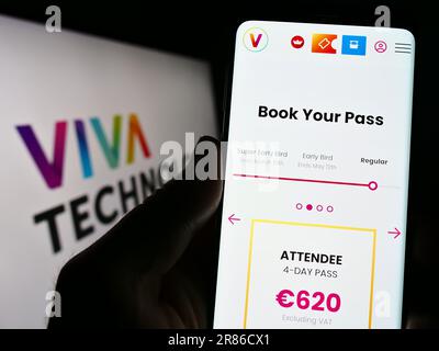 Person, die ein Mobiltelefon mit einer Webseite der französischen Konferenz Viva Technology (VivaTech) auf dem Bildschirm mit Logo hält. Konzentrieren Sie sich auf die Mitte des Telefondisplays. Stockfoto